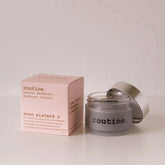 Routine Moon Sisters natural deodorant jar - pink packaging box beside opened glass jar showing charcoal-grey cream deodorant - activated charcoal and prebiotic formula for sensitive skin