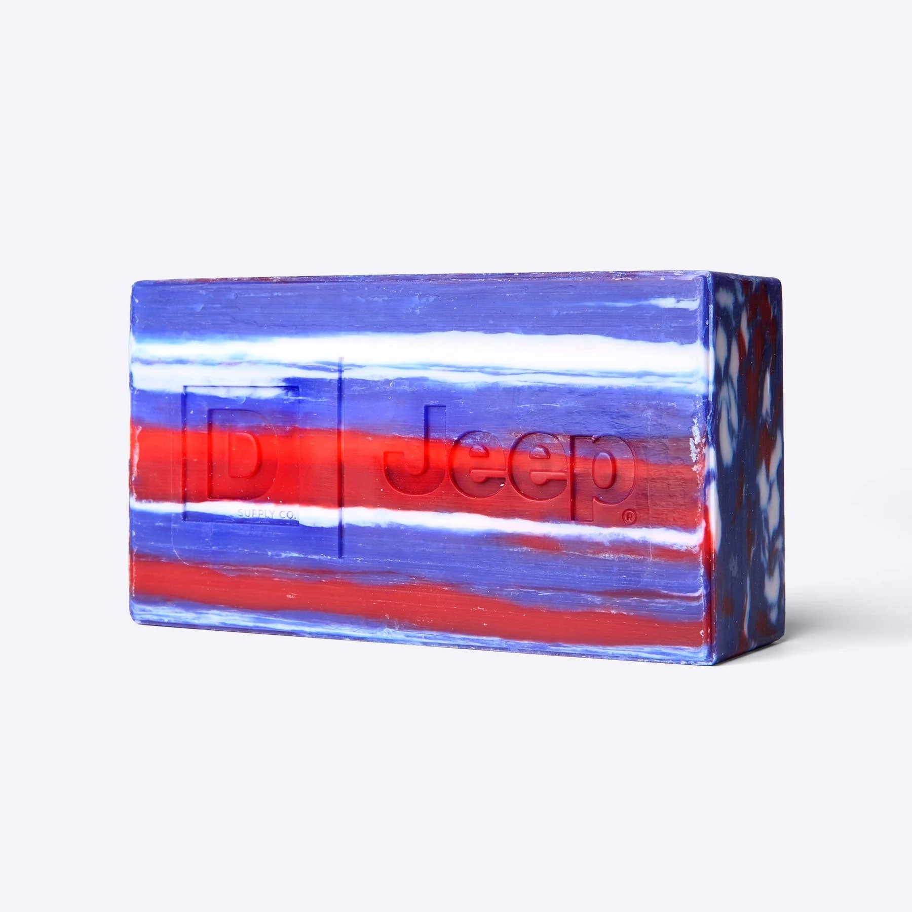 Close-up of the triple-milled Duke Cannon Jeep brick of soap with red, white, and blue marbled stripes and embossed D and Jeep® logos