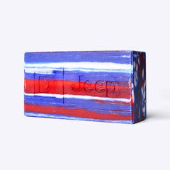 Close-up of the triple-milled Duke Cannon Jeep brick of soap with red, white, and blue marbled stripes and embossed D and Jeep® logos
