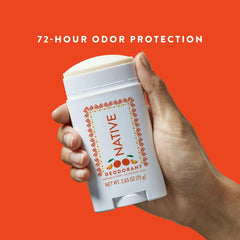 Hand holding a Native Jarritos Mandarin deodorant stick against an orange background with '72-Hour Odor Protection' text.