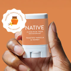 Native aluminum-free deodorant stick with toasted vanilla & honey scent held by a hand against an orange background.