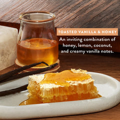 Glass of honey, honeycomb, and vanilla beans on a wooden surface with text describing the flavor profile.