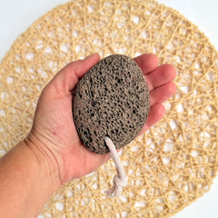 Hand holding a textured pumice stone with a woven mat background