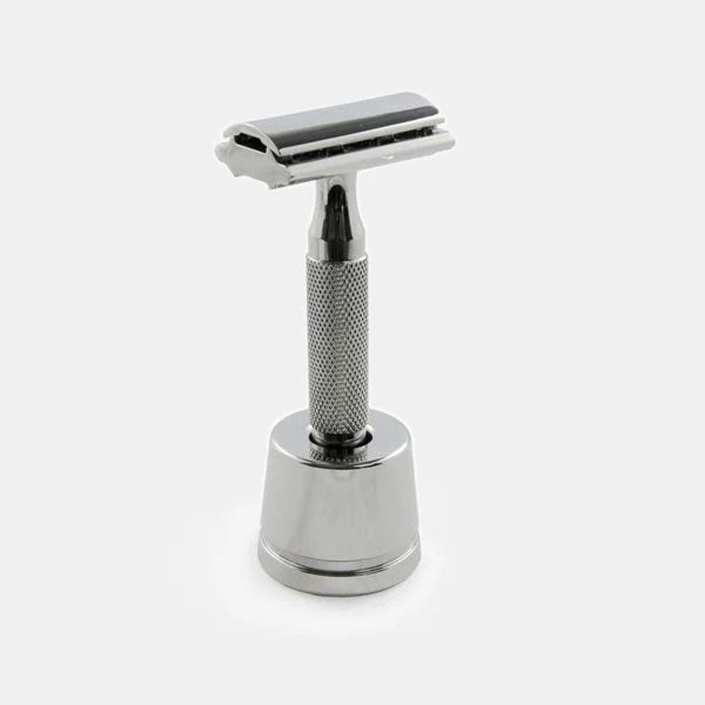 Rockwell safety razor displayed upright in chrome inkwell stand demonstrating elegant presentation and functional storage on bathroom counter.