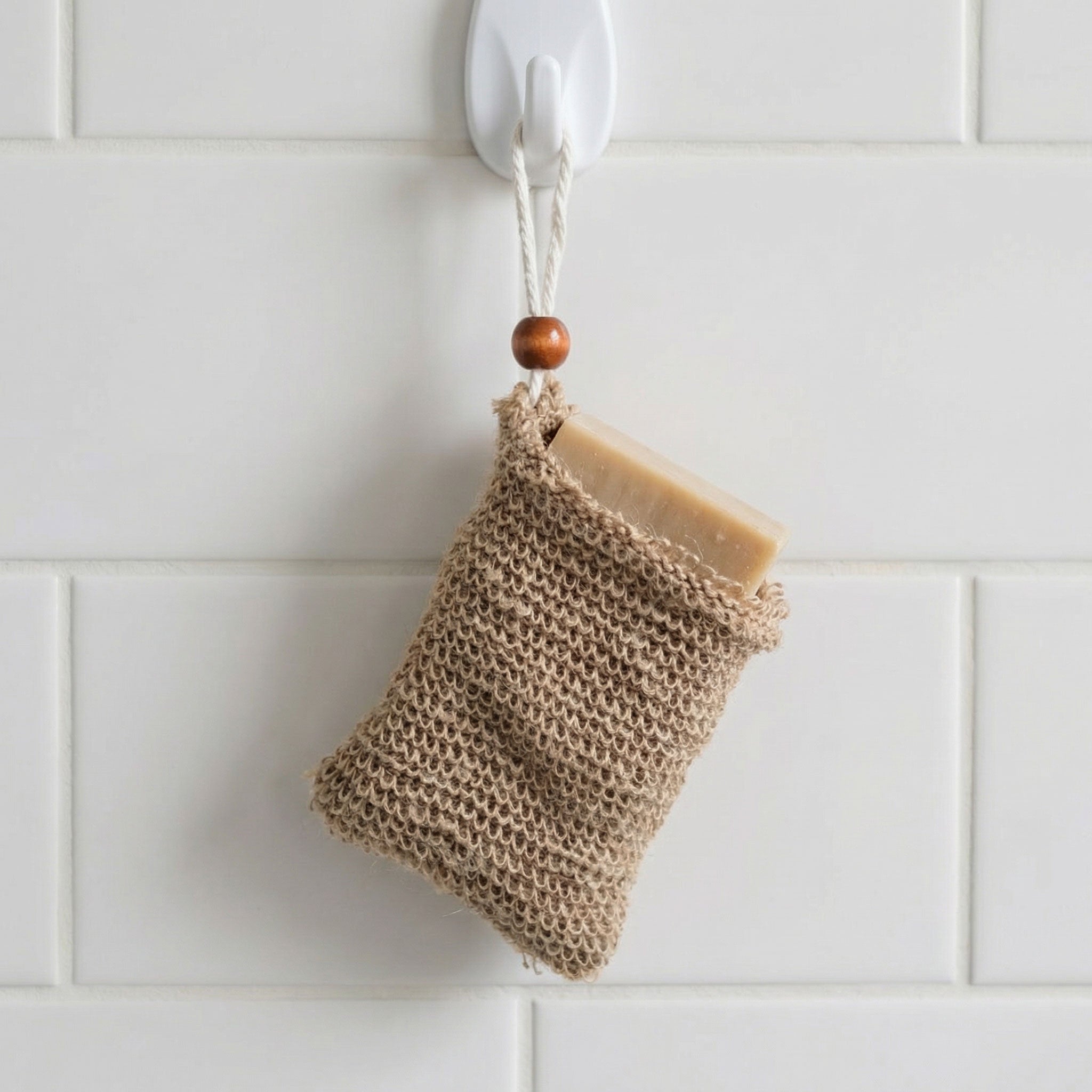 Soap saver bag hanging from bathroom hook with bar soap inside demonstrating storage use
