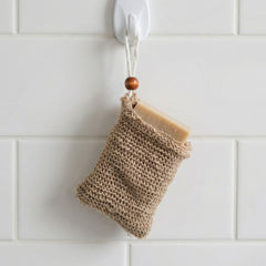 Soap saver bag hanging from bathroom hook with bar soap inside demonstrating storage use