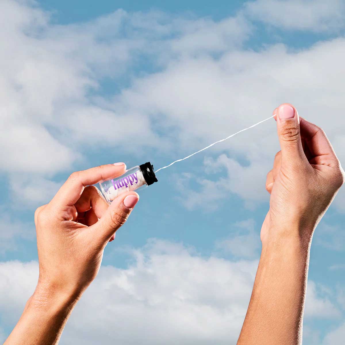 huppy dental floss outdoor lifestyle shot - hands pulling floss from glass jar against blue sky background, emphasizing natural and eco-friendly qualities