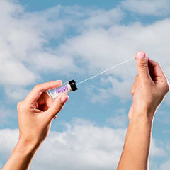 huppy dental floss outdoor lifestyle shot - hands pulling floss from glass jar against blue sky background, emphasizing natural and eco-friendly qualities