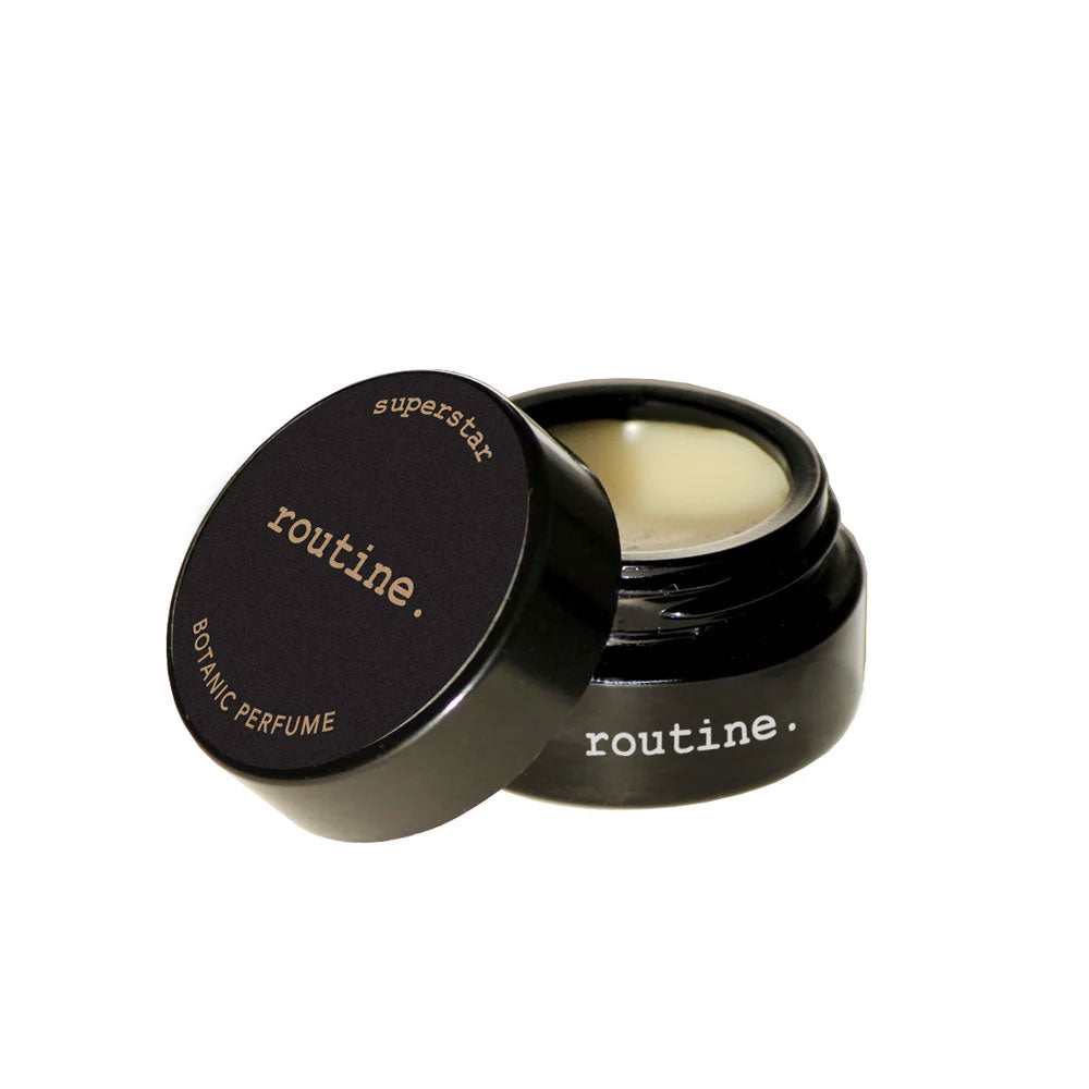 Routine Superstar solid perfume - black glass jar with black label open revealing golden balm texture 