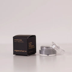 Routine Superstar mini deodorant showing black packaging with gold text next to open glass jar containing charcoal-grey natural deodorant with activated charcoal