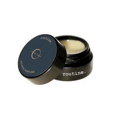 Routine The Class solid perfume - black glass jar with navy blue label open revealing golden balm texture