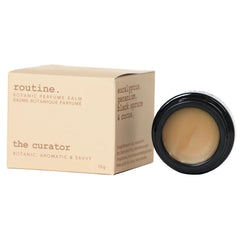 Routine The Curator solid perfume - cream packaging box with botanical scent description and black jar showing smooth balm texture
