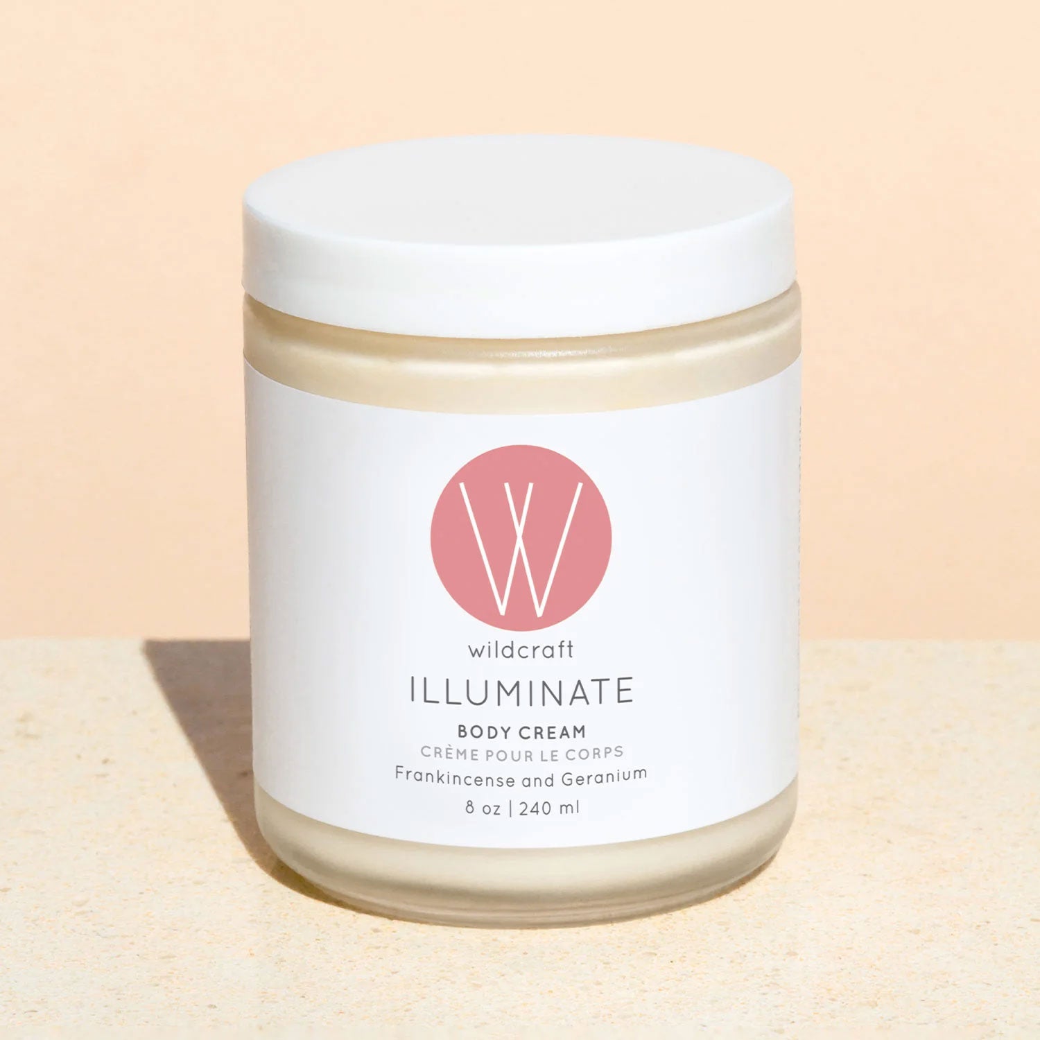A jar of Wildcraft Illuminate Body Cream with a white label, featuring the product name and the scent, Frankincense and Geranium.
