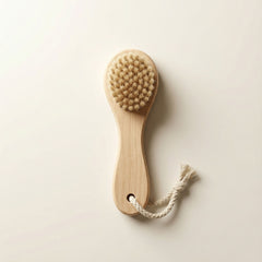 Wooden brush with bristles and a rope handle on a light beige background