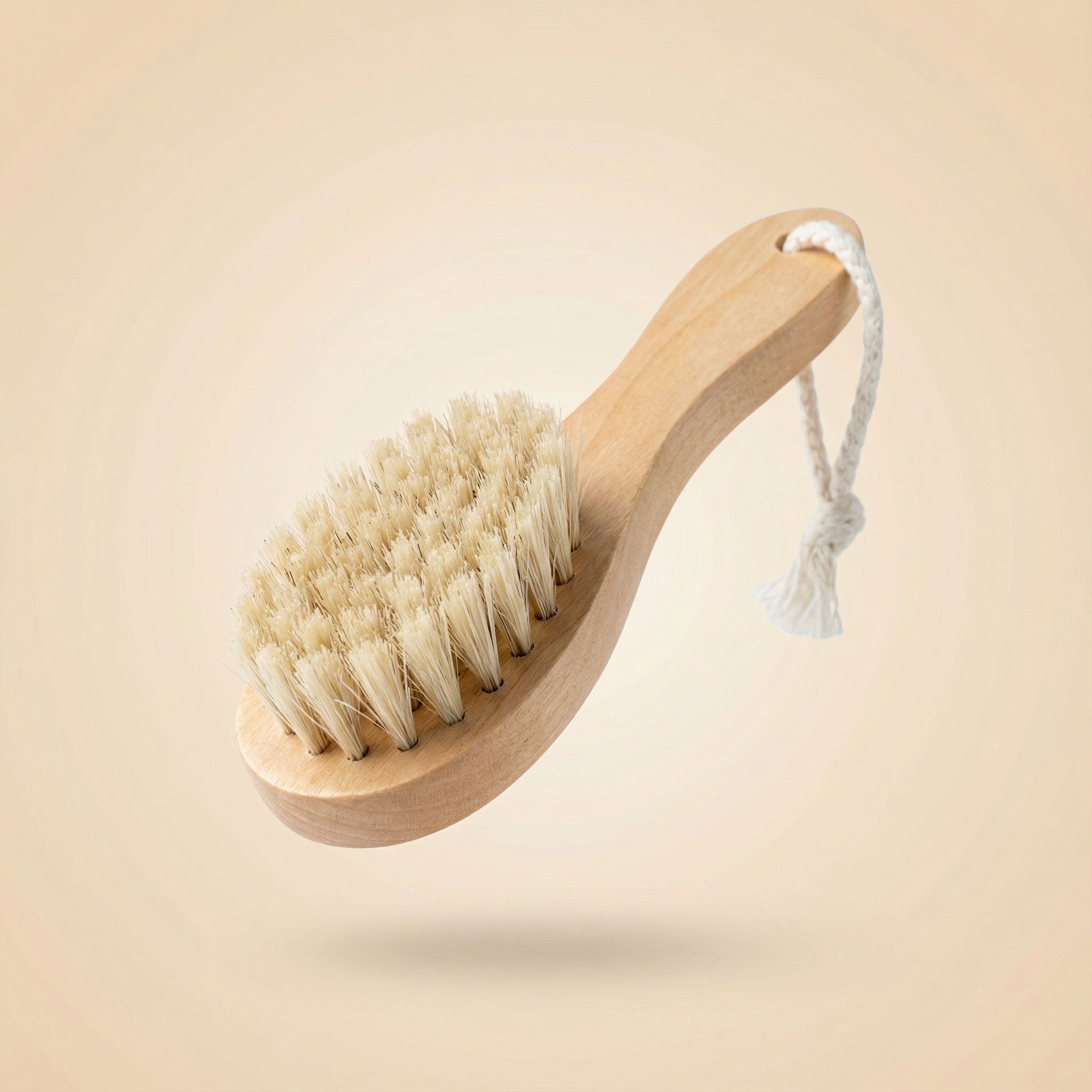 Natural wooden facial cleansing brush with soft boar bristles and cotton hanging rope floating against neutral background, showing ergonomic handle design